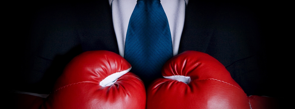 Stock image of person wearing business suit and boxing gloves